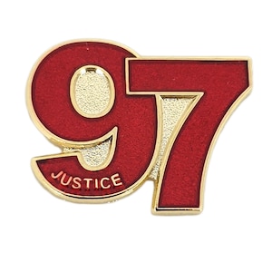 Könnte beinhalten: Eine goldfarbene Anstecknadel mit der Nummer 97 in roter Emaille. Das Wort "JUSTICE" ist auf der Unterseite der Anstecknadel eingraviert.