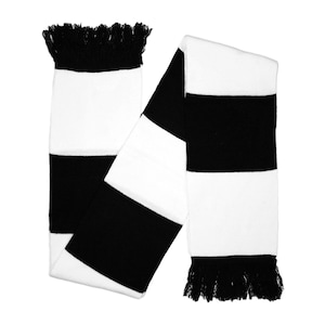 May include: A black and white striped scarf with fringe at both ends. The scarf is made of a soft, knitted material. The scarf has alternating black and white stripes.