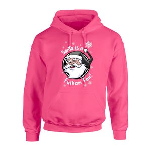 May include: Pink hooded sweatshirt with a white graphic of Santa Claus wearing a black hat and a white beard. The graphic says "Santa is a Fulham Fan!" with snowflakes around the graphic.