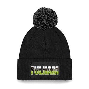 May include: Black knit beanie with a black pom pom and a patch that says "FULHAM" with a picture of a soccer field in the background.