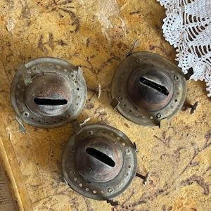 May include: Three antique brass lamp parts with a circular design and a hole in the center. The parts are worn and have a patina finish.