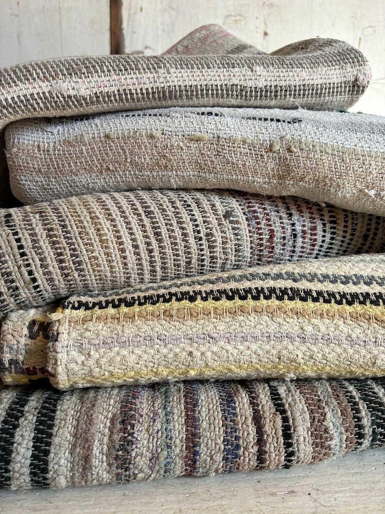 tappeti tessuti in varie tonalità di marrone, beige e nero. I tappeti hanno un motivo a strisce e sono realizzati in fibra naturale.  coperte con toni della terra. Tappeti e arazzi antichi tessuti a mano