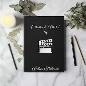 May include: A black book with the text "Written & Directed by Colleen Anderson" and a white silhouette of a clapperboard.