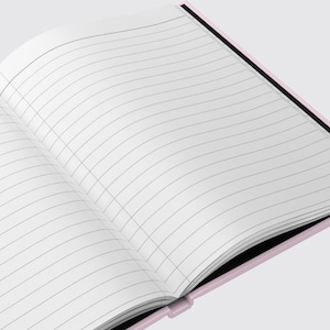 May include: A pink notebook with lined pages, open to reveal a blank page. The notebook has a black spine and a black edge.