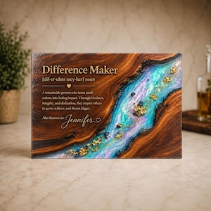 May include: A rectangular wooden plaque featuring a central resin river in shades of blue, purple, and white with gold leaf accents. The text reads: Difference Maker [dif-er-uhns mey-ker] noun. A remarkable person who turns small actions into lasting impact. Also known as: Jennifer.