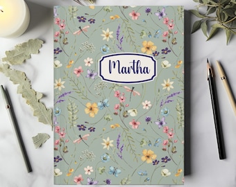 May include: A green journal with a floral pattern and the name "Martha" in a navy blue banner. The flowers are in shades of pink, purple, yellow, and blue.