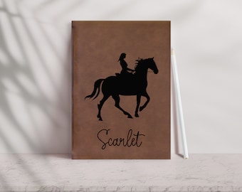 May include: Brown leather journal with a black silhouette of a person riding a horse. The name "Scarlet" is written in cursive below the image.