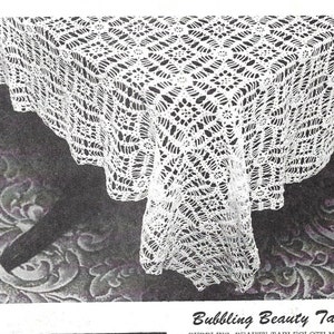 May include: A white crocheted tablecloth with a delicate, lacy pattern. The tablecloth is square and has a scalloped edge. The text "Bubbling Beauty Tablecloth" is visible at the bottom of the image.