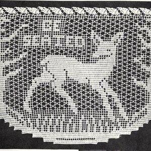 May include: White crochet doily with a delicate design featuring two deer standing in a forest. The doily has a scalloped edge.