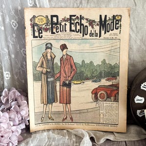 May include: Vintage French fashion magazine cover, "Le Petit Echo de la Mode," featuring an illustration of two women in stylish coats and dresses. The cover art includes cars and trees, with text in French.