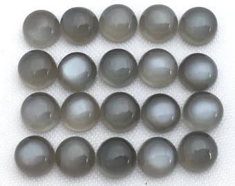 May include: Twenty gray cabochon gemstones with a pearlescent sheen. The stones are round and smooth, and they are arranged in three rows.