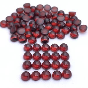 May include: A large group of red round glass cabochons, some are loose and others are arranged in a grid pattern.