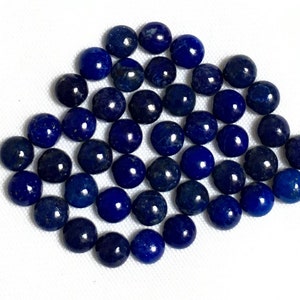 May include: A collection of 40 round, dark blue lapis lazuli gemstone cabochons. The cabochons are smooth and polished.