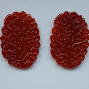 K&ouml;nnte beinhalten: Zwei rote Karneol-Anh&auml;nger mit einem komplizierten geschnitzten Blumenmuster.