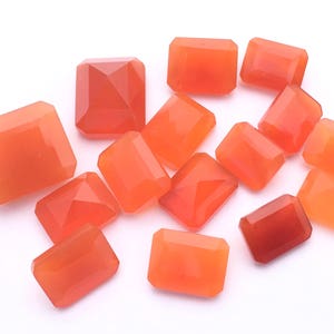 Puede incluir: Una colecci&oacute;n de 12 piedras preciosas de cornalina naranja, talladas en forma rectangular. Las piedras son lisas y pulidas, con un tono naranja c&aacute;lido.
