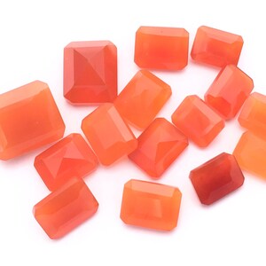 Puede incluir: Una colecci&oacute;n de 13 piedras preciosas de cornalina naranja, talladas en forma rectangular, presentadas sobre un fondo blanco.