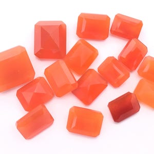 Puede incluir: Una colecci&oacute;n de 14 piedras preciosas de cornalina naranja, talladas en forma rectangular con bordes facetados. Las piedras est&aacute;n dispuestas sobre un fondo blanco.