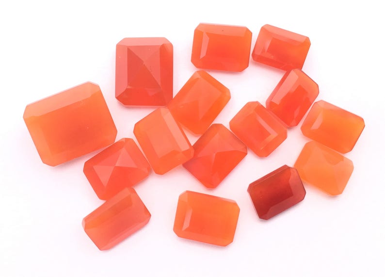 Puede incluir: Una colecci&oacute;n de 14 piedras preciosas de cornalina naranja, talladas en forma rectangular con bordes facetados. Las piedras est&aacute;n dispuestas sobre un fondo blanco.