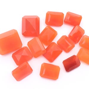 Puede incluir: Una colecci&oacute;n de 14 piedras preciosas de cornalina naranja, talladas en forma rectangular, presentadas sobre un fondo blanco.