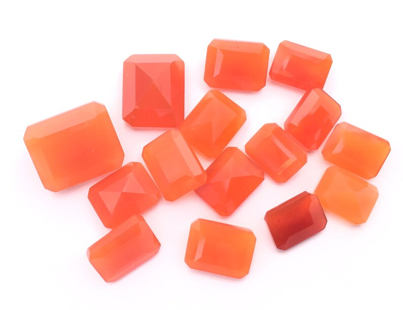 Puede incluir: Una colecci&oacute;n de 14 piedras preciosas de cornalina naranja, talladas en forma rectangular, presentadas sobre un fondo blanco.