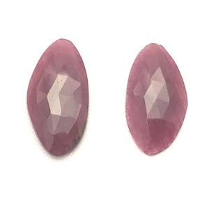 May include: Two pink faceted gemstone cabochons, each with a unique, irregular shape.