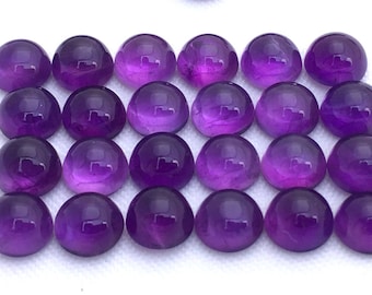 May include: A collection of 25 round, purple amethyst cabochons. The cabochons are arranged in a grid pattern on a white surface.
