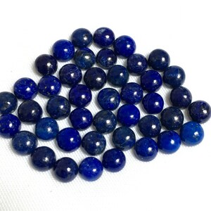 May include: A collection of round, dark blue lapis lazuli cabochons. The stones are smooth and polished, with a slight sparkle.