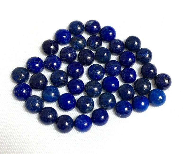 May include: A collection of round, dark blue lapis lazuli cabochons. The stones are smooth and polished, with a slight sparkle.