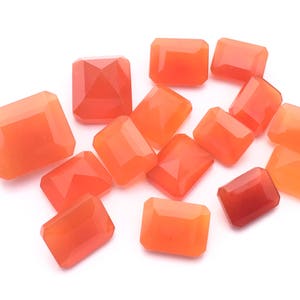 Puede incluir: Una colecci&oacute;n de 14 piedras preciosas de cornalina naranja, talladas en forma rectangular, presentadas sobre un fondo blanco.