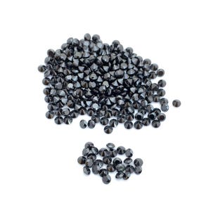 May include: A large pile of black round gemstones, with a smaller pile of black round gemstones to the side.