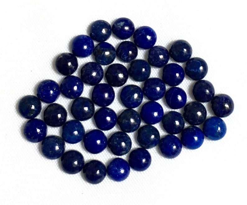 May include: A collection of 40 round, smooth, dark blue lapis lazuli cabochons. The cabochons are arranged in a loose, overlapping pattern.