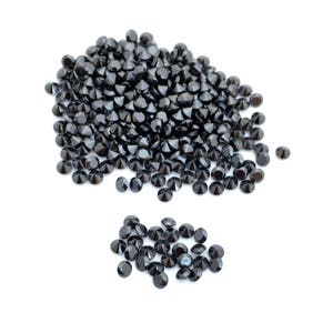 May include: A large pile of black round gemstones, with a smaller pile of black round gemstones to the side.