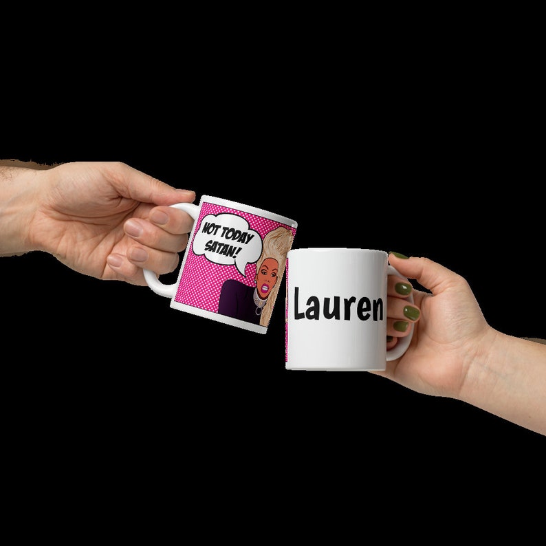 May include: Two white ceramic mugs. One mug has a pink background with a cartoon image of a woman with blonde hair and the text "Not today Satan!" The other mug has the name "Lauren" printed in black.