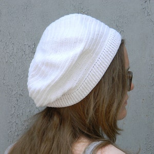 May include: A white crocheted beanie hat with a slouchy fit.