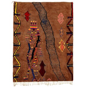 May include: A brown Moroccan rug with a geometric pattern in shades of red, yellow, blue, and pink. The rug has a fringe border.