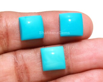 May include: Three square-cut turquoise gemstones. The gems are a vibrant, solid turquoise color and appear smooth and polished. The gems are displayed against a skin-toned background.