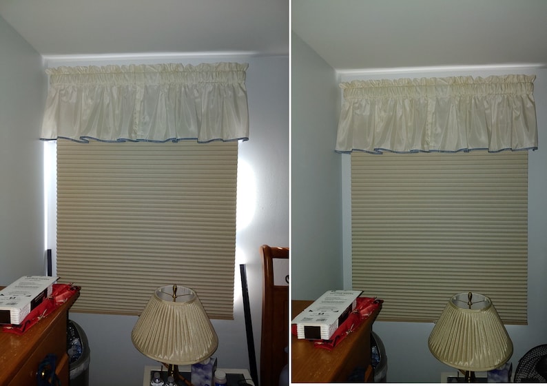 May include: A window featuring a beige pleated cellular shade and a cream-colored ruffled valance with a thin blue trim along the bottom edge. The window is positioned above a wooden nightstand with a lamp and a box of window shade hardware.
