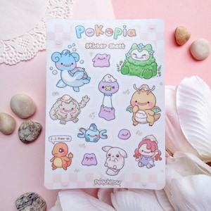 May include: A sticker sheet featuring various cartoon characters in pastel colors. The sheet includes the text "Pokepia" and "Sticker Sheet". The characters include a blue turtle-like creature, a green creature, and a yellow dragon-like character.