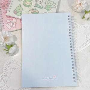 May include: A light blue spiral bound notebook with the word "peachirou" printed on the front cover.
