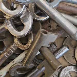 May include: A close-up shot of a collection of antique keys. The keys vary in size, shape, and metal finish, with some showing signs of rust and wear. The collection includes keys with ornate designs and simple, functional styles.