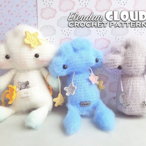Peut inclure: Trois peluches en forme de nuage crochetées, une blanche avec une étoile jaune, une bleue avec une étoile rose et une grise avec une lune en argent. Chaque peluche a des yeux noirs et une petite étiquette.