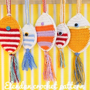 May include: Five handmade crochet ornaments in various colors, including orange, white, red, and blue. Each ornament has a unique design with stripes, buttons, and tassels. The text "Elandan crochet pattern" is visible at the bottom.