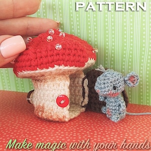 Puede incluir: Una casa de hongo de ganchillo con la parte superior roja y la inferior blanca. Un pequeño ratón de ganchillo se sienta junto a la casa. La imagen tiene el texto "Elendan Crochet Pattern" y "Make magic with your hands".
