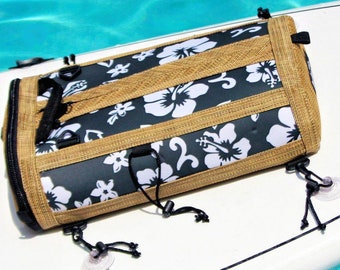 May include: A black and white floral patterned bag with brown straps and suction cups. The bag is attached to a white surfboard.