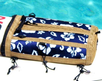 May include: A blue and white floral print zippered pouch with brown trim and black straps. The pouch is made of a woven fabric and has a zipper closure.