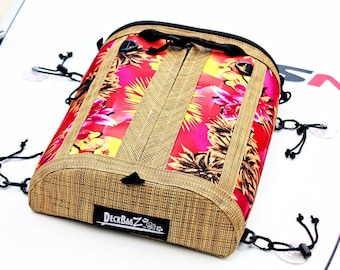 May include: A tan and red waterproof bag with a tropical print and the text "DeckBagZ" on the bottom. The bag has a zipper closure and multiple straps with suction cups.