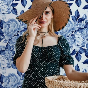Woman posing with flower pattern wallpaper in the background.