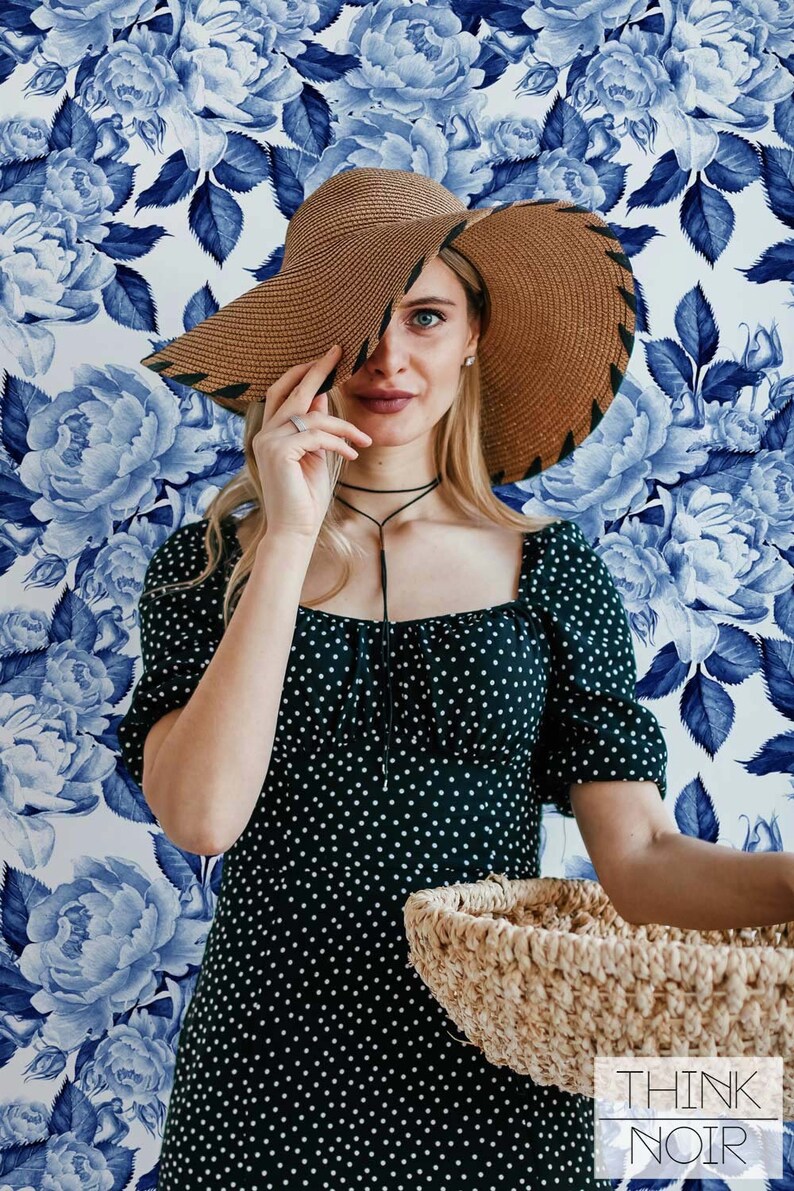 Woman posing with flower pattern wallpaper in the background.