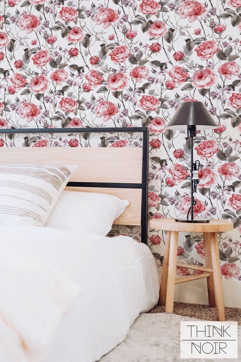 Bedroom with a pink rose pattern wallpaper in the background.