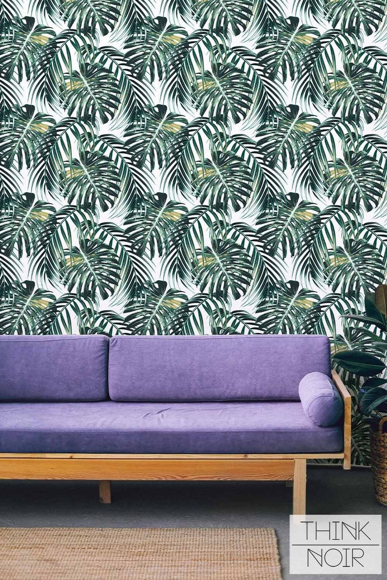 Vibrant monstera leaf pattern wallpaper in a modern living room with an accent sofa.